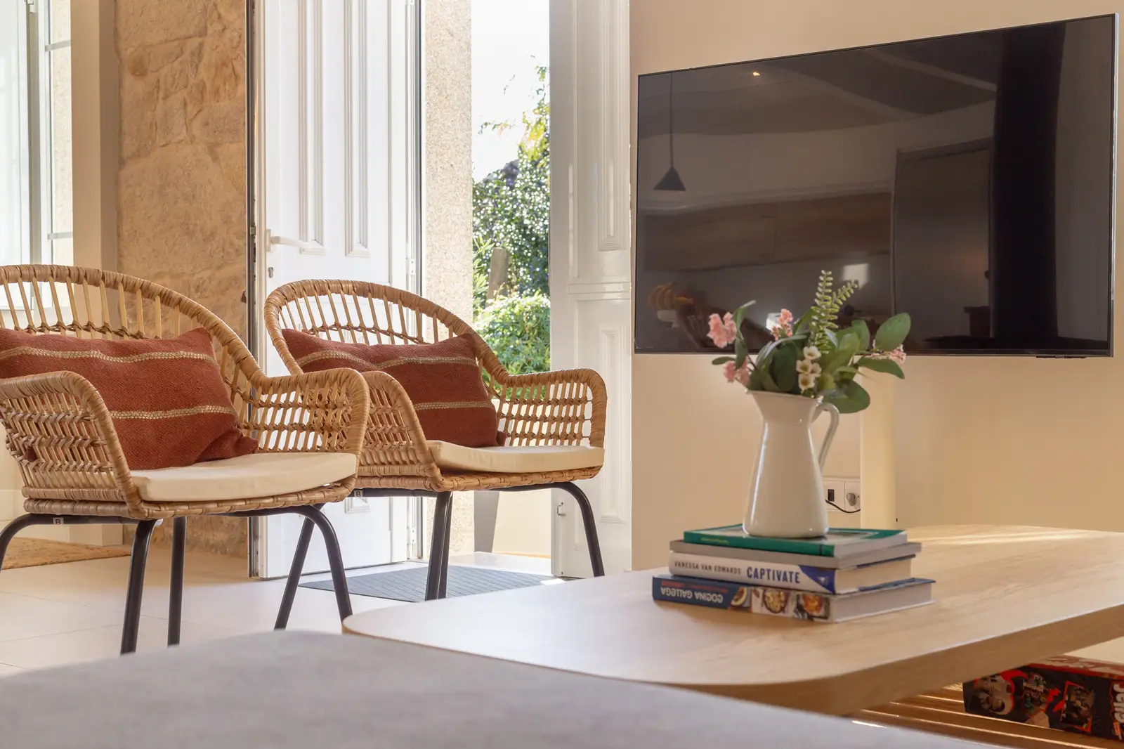 Sala de la casa siavo con mesa 2 silla rusticas con cojines y televisor anclado a la pared