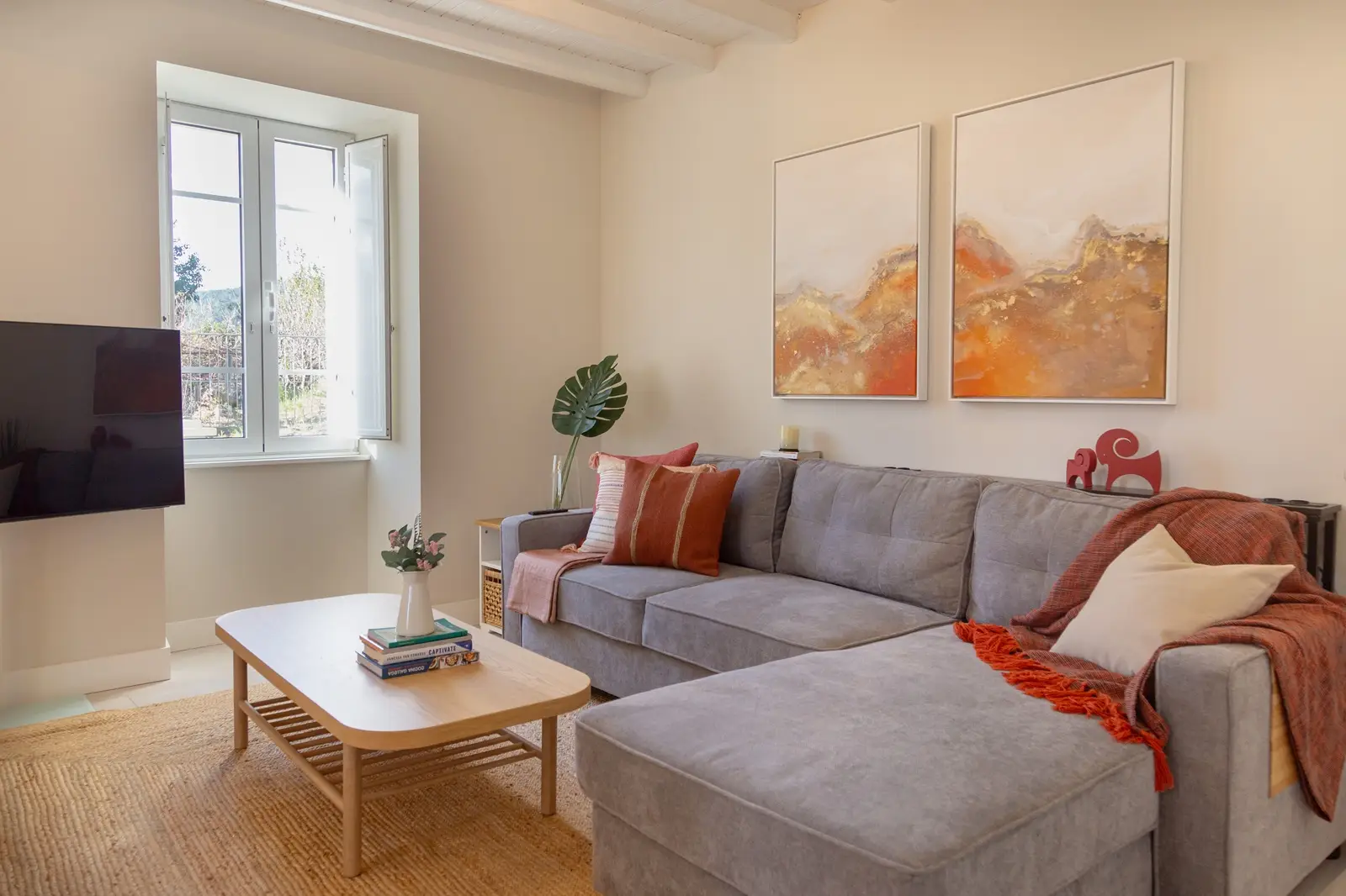 sala de la casa siavo con sofa grande en l y mesa de centro en el fondo una venta grande da iluminación al espacio