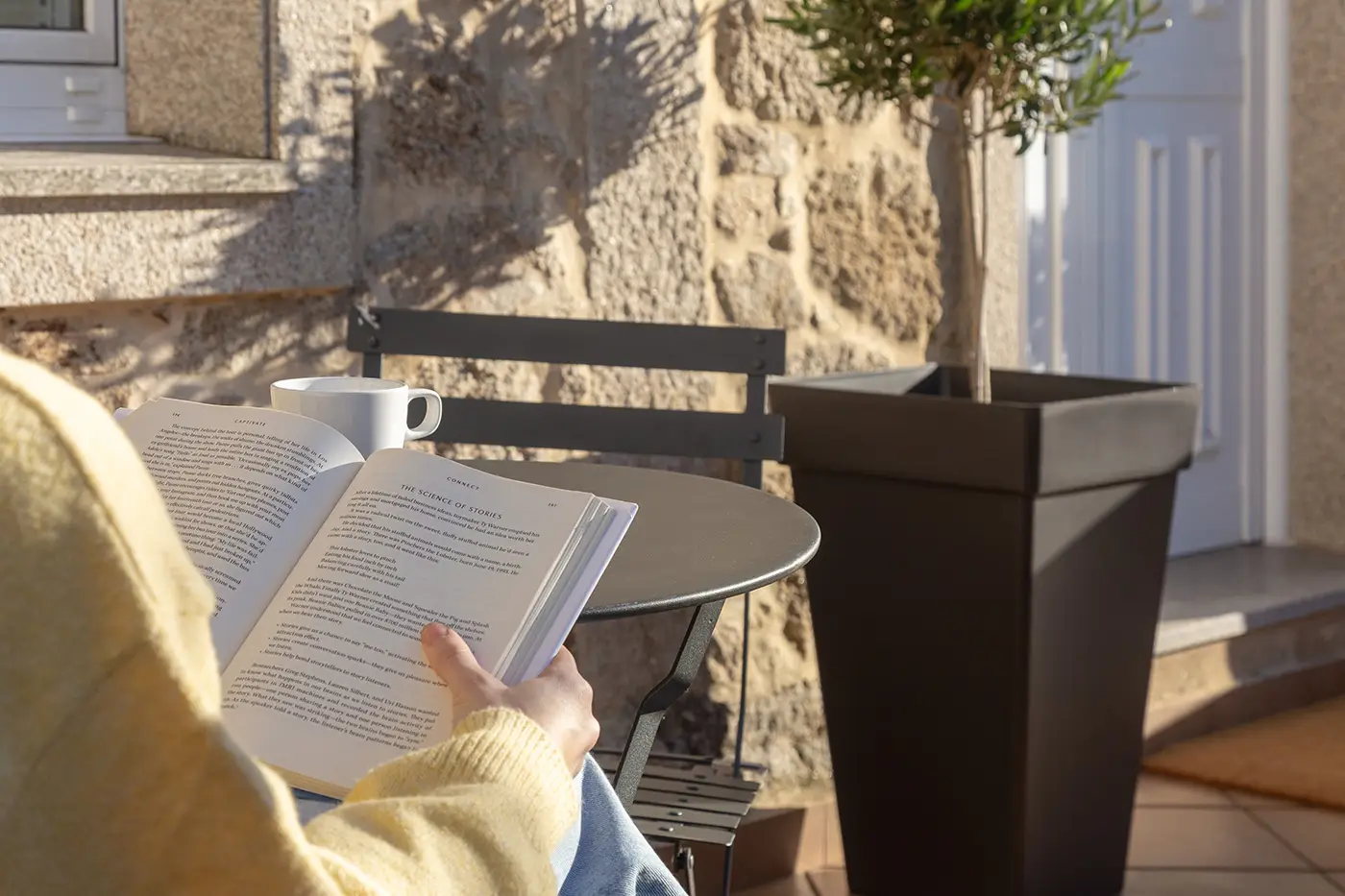 Espacio exterior de casa de piedra con mobiliario para lectura en el jardin
